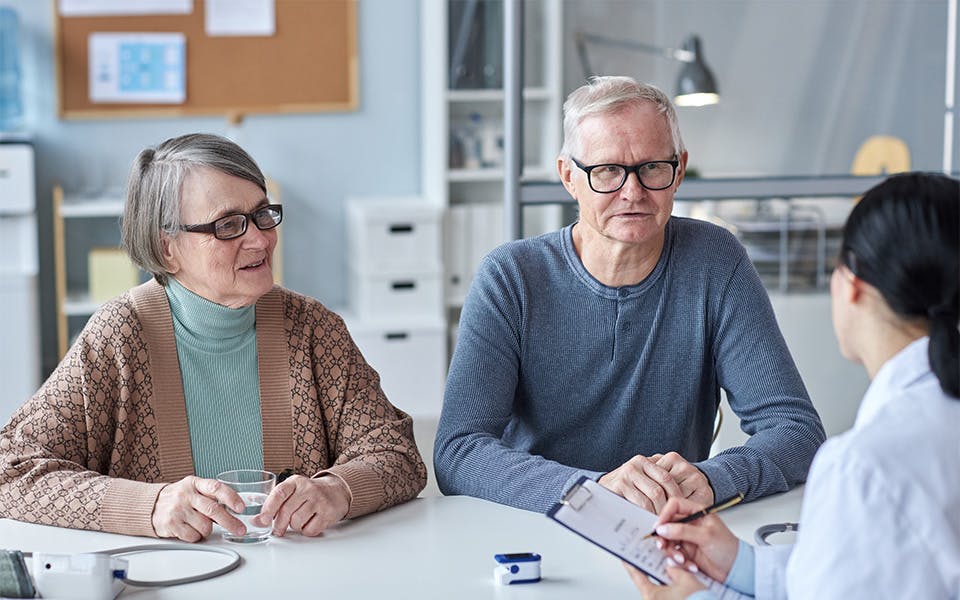 Smiling elderly couple consulting with an audiologist
