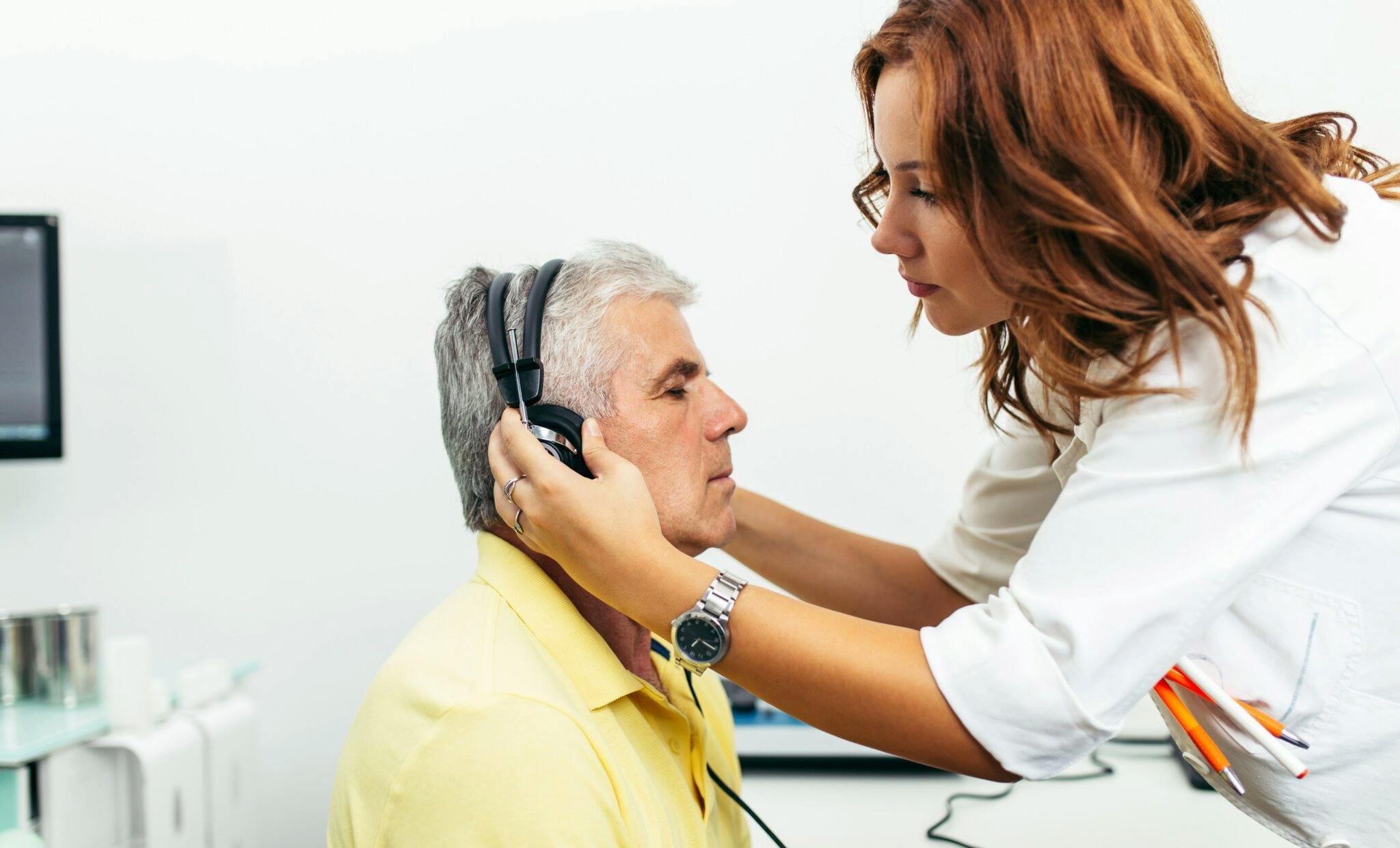 Woman Audiologist putting headphones on a man