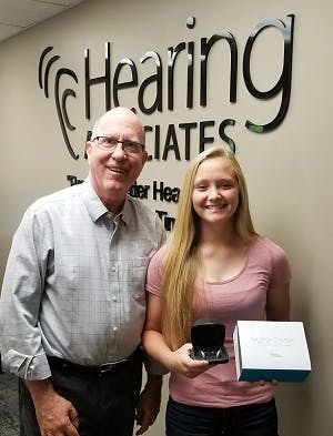 Smiling man and student holding an award while standing in Hearing Associates office