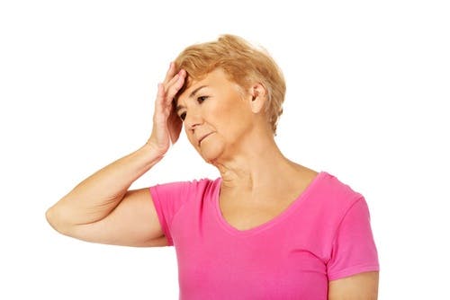 Older woman with hand on her head and looking exasperated as if experiencing balance issues