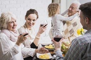 Family sitting around a dining room table raising glasses in a toast