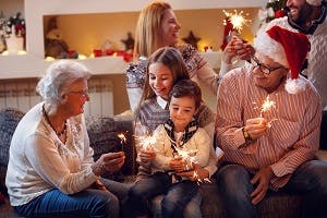 Smiling family holding sparklers and wearing Christmas-themed clothing