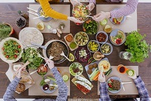 Overhead view of healthy meal on dining room table and four people sharing food