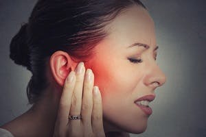 Woman in pain with hand on head experiencing tinnitus symptoms