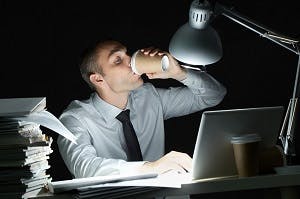 Image of Man using computer drinking coffee, tinnitus triggers.
