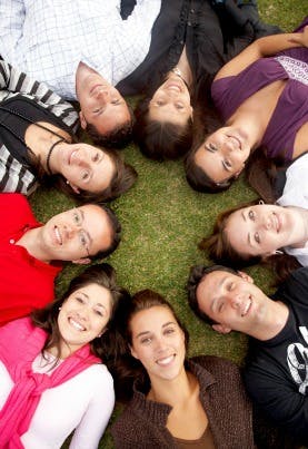 Group of smiling friends laying on the grass