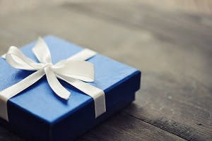 Blue gift box with white bow on a wooden table