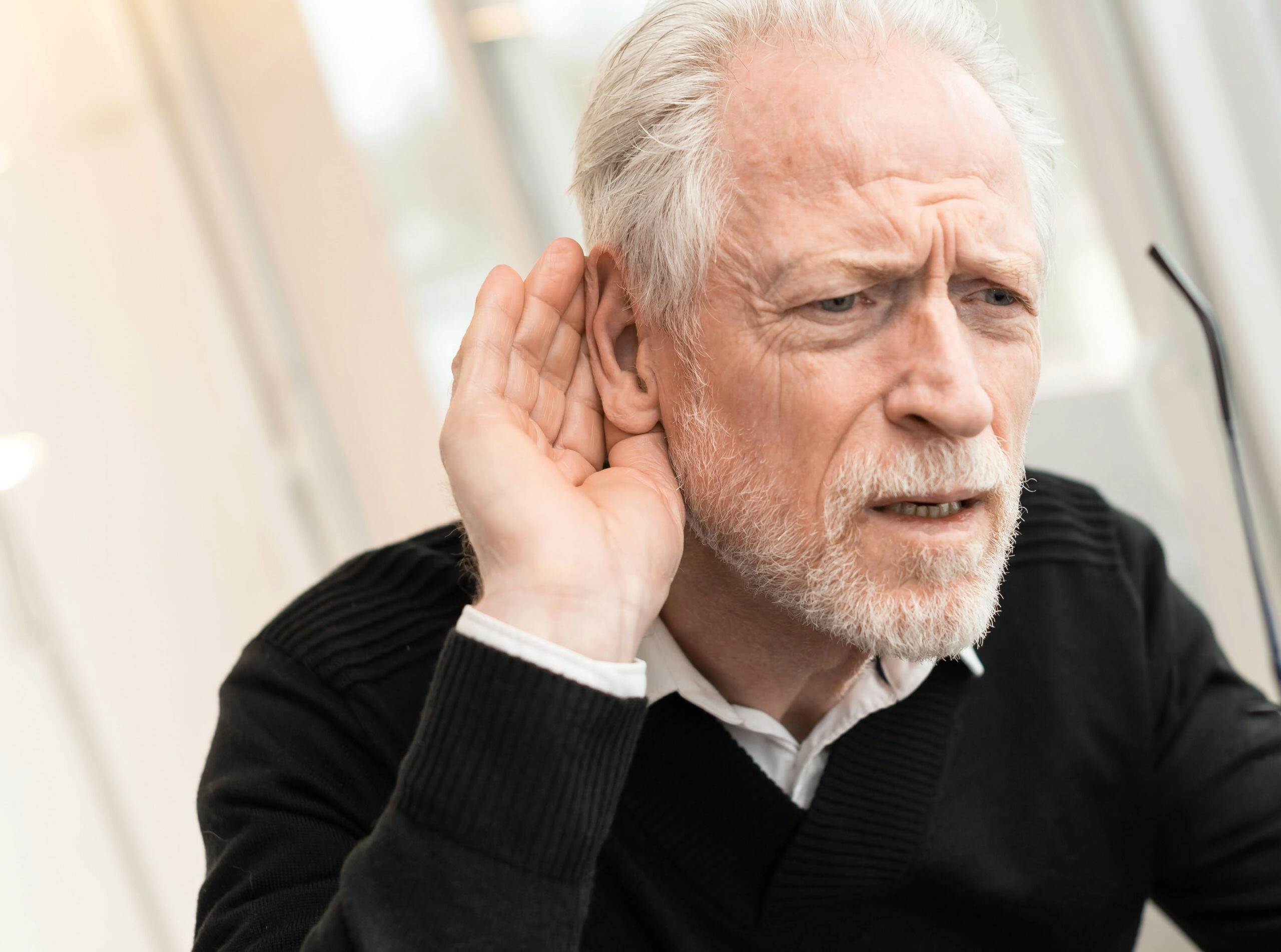 Man holding had to ear to hear better