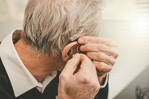 man putting on hearing aid