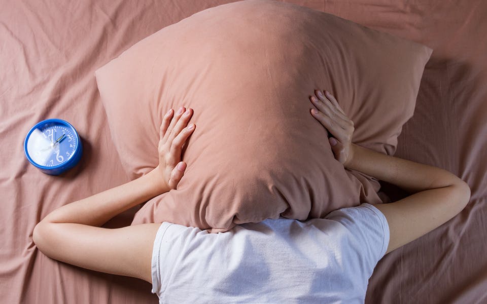 person covering head with pillow