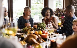 Group of people sitting around a table celebrating Thanksgiving
