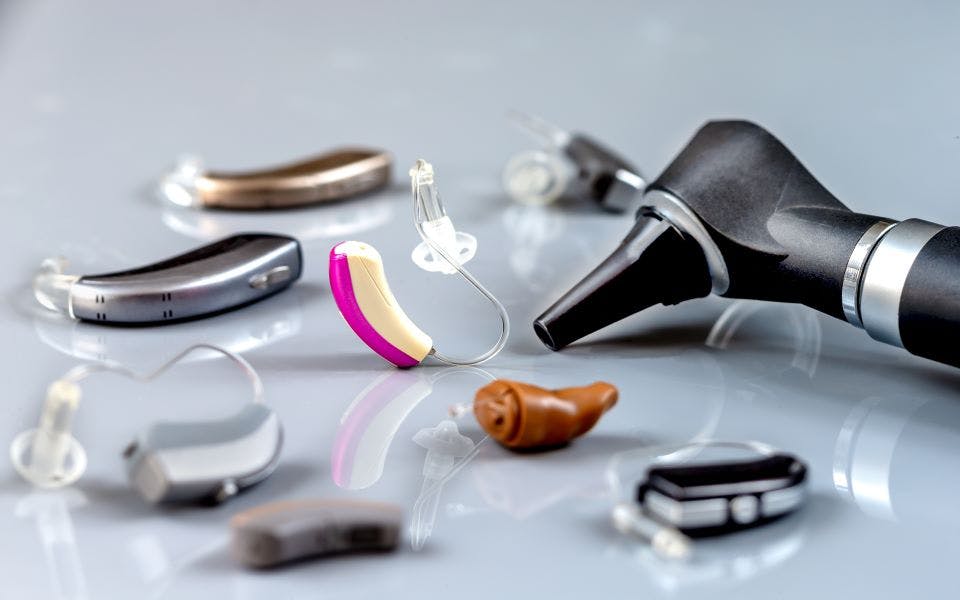 Different hearing aid brands and styles and an otoscope on a table