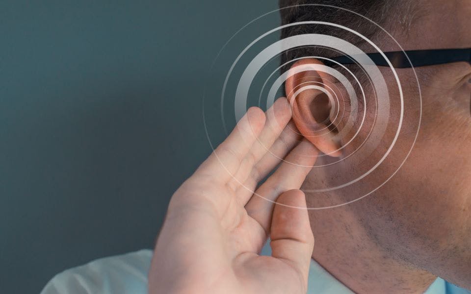 Sensorineural hearing loss concept - Man putting his hand on his ear with a circular white overlay over his ear and empty space on the left/