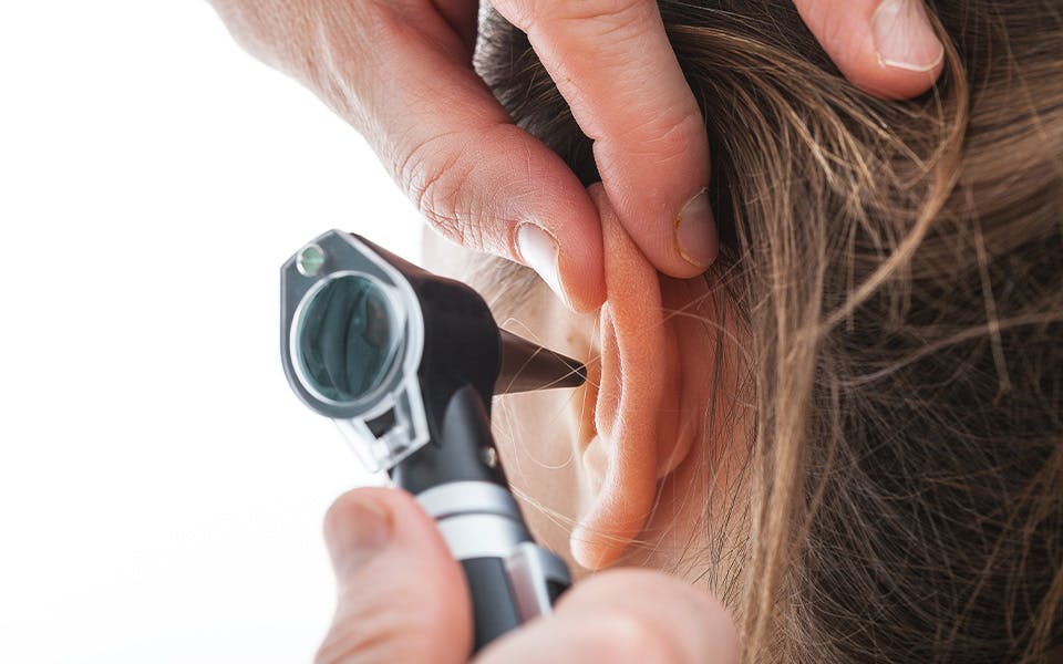 Audiologist examining a patient's ear with an otoscope
