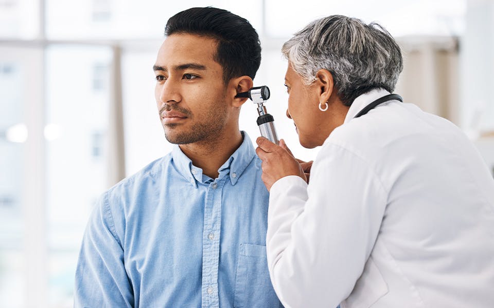 An audiologist checking a patient's ear