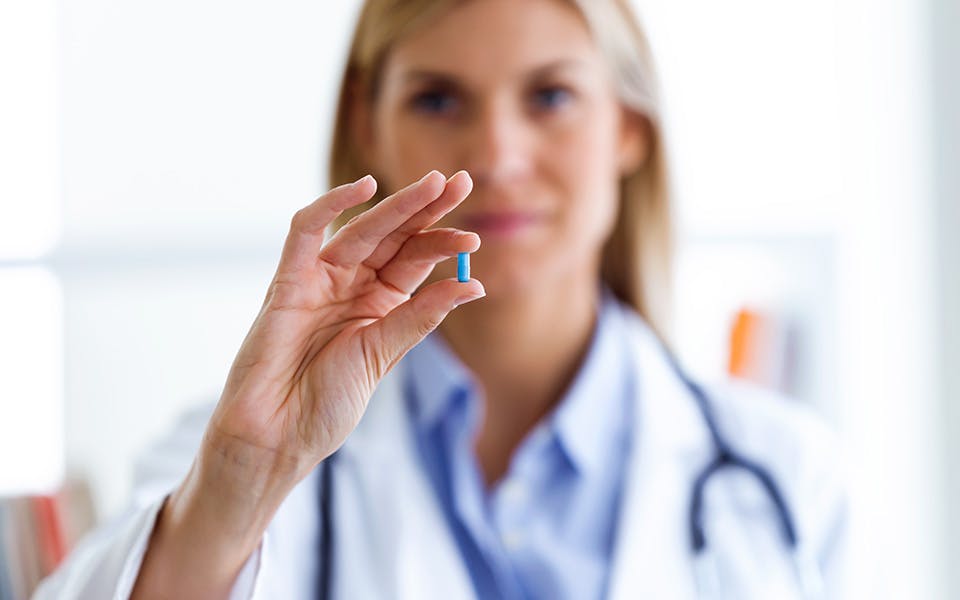 A female doctor holding a hearing medication tablet