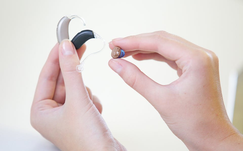 Three different hearing aids in female hands